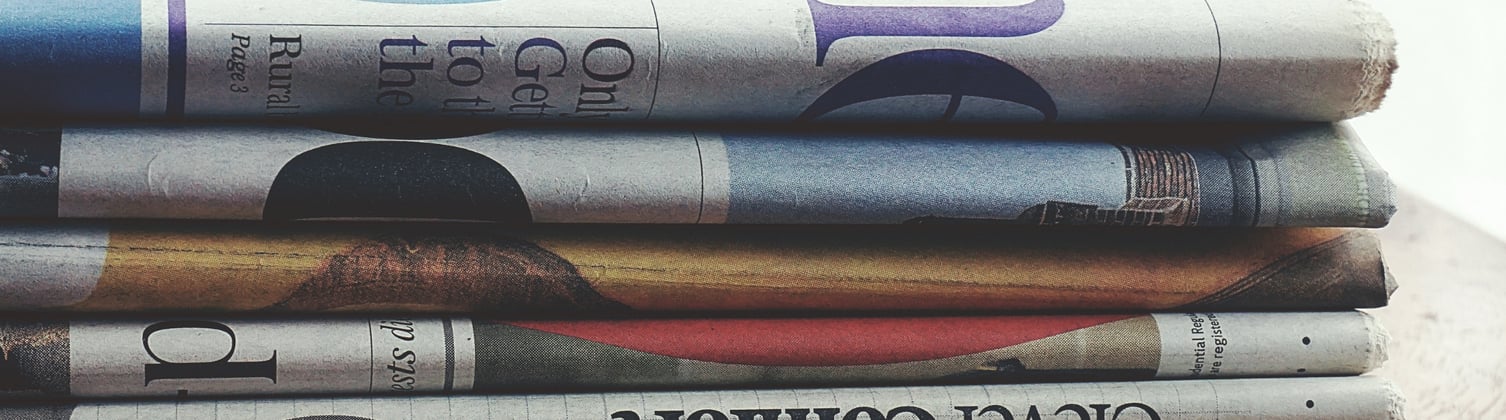 A neatly folded stack of newspapers on a table.