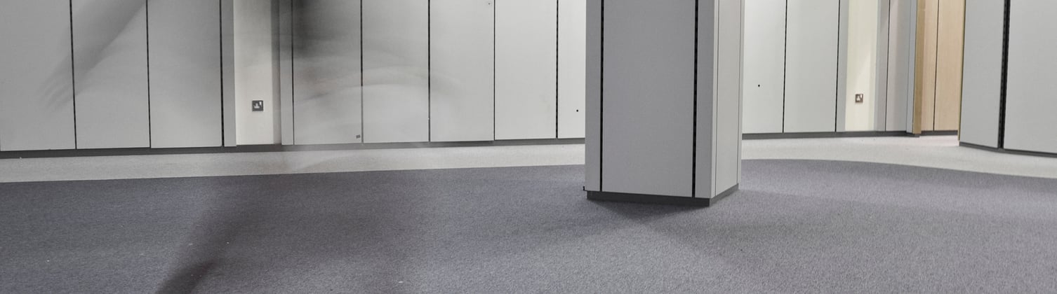 A shadow figure of a man in a motion blur going through a grey room.