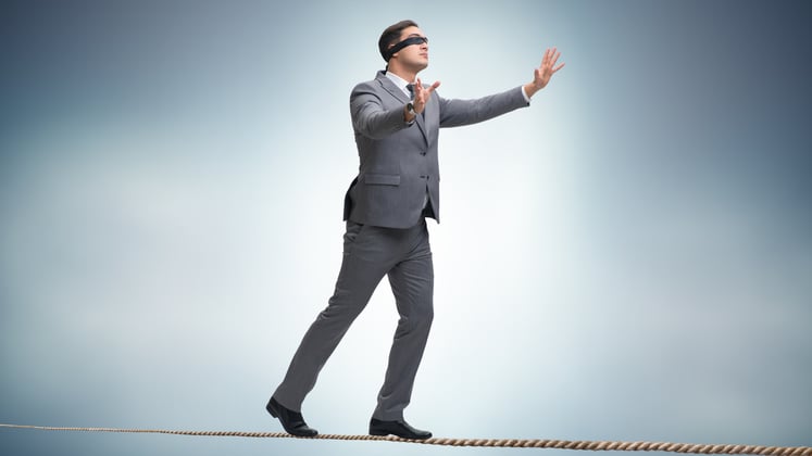 Man in a suit, upright, balancing himself on a tightrope.