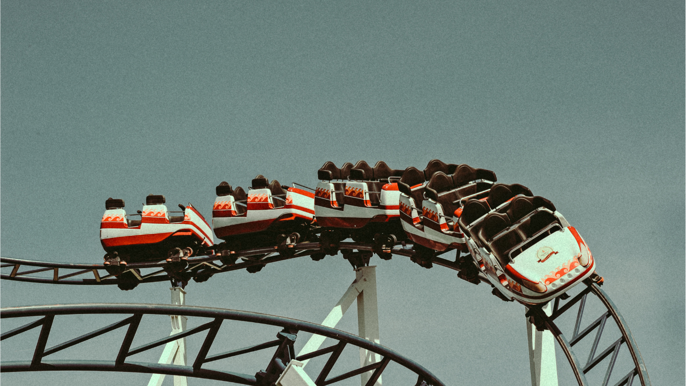 Snippet of a rollercoaster going up a track with a grey sky background.