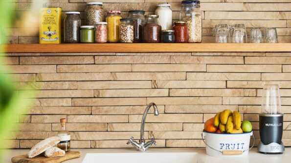 Kitchen sink with containers of food on shelf and fruit in bowl