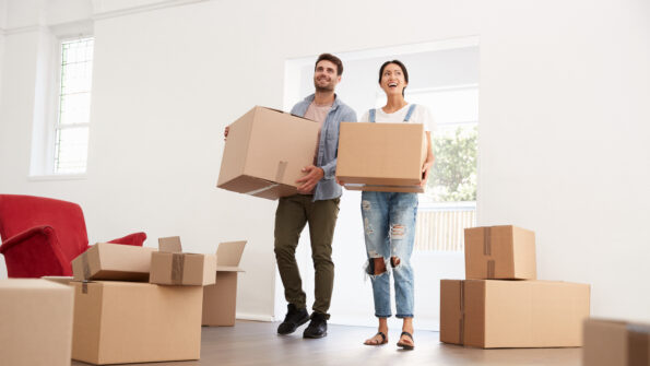 Two people holding moving boxes in new home