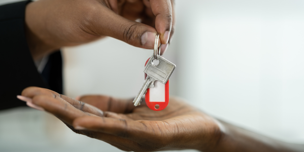Person handing over house keys to another person